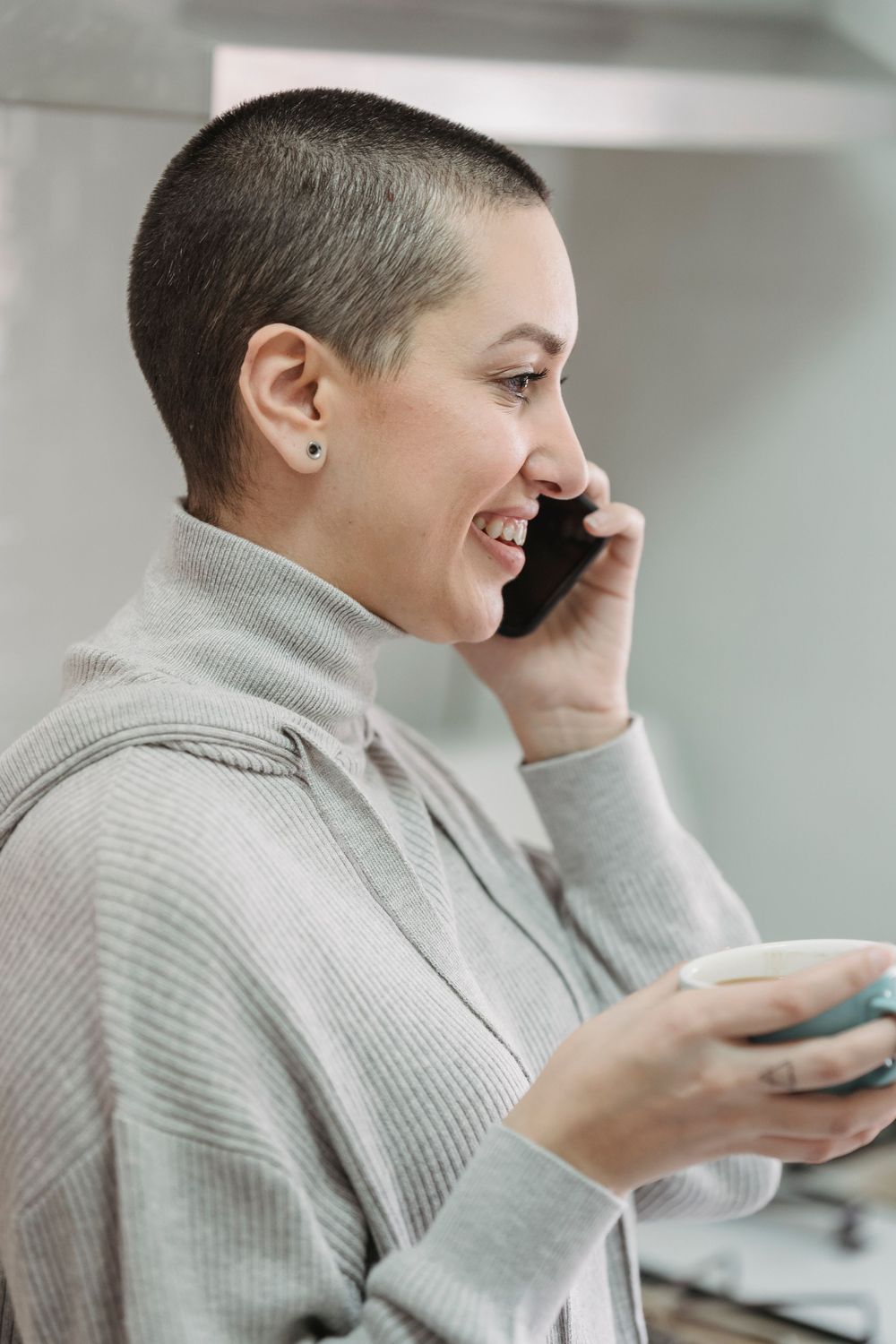 Woman smiling on her phone with a cup of tea