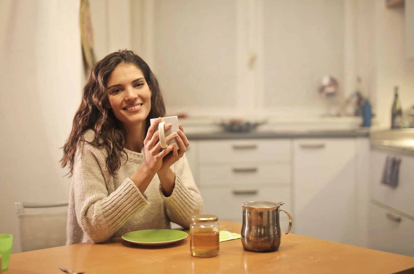 Woman smiling with a cup of tea in her kitchen